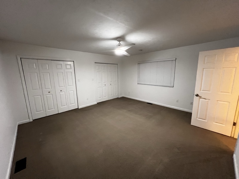 Bedroom with two sets of folding closet doors, ceiling fan, and natural light from a single window