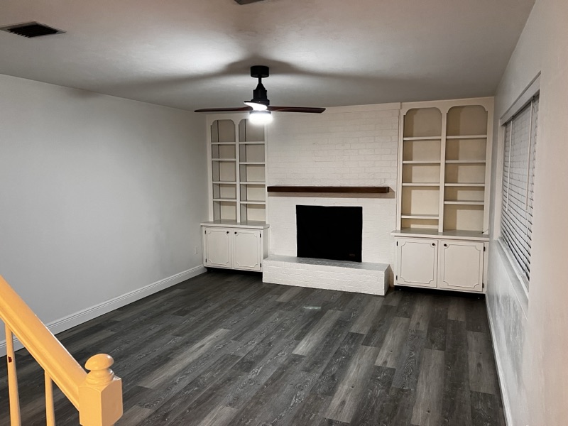 Living room with white-painted brick fireplace and built-ins
